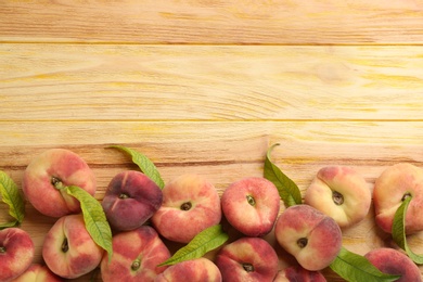 Photo of Fresh ripe donut peaches on wooden table, flat lay. Space for text