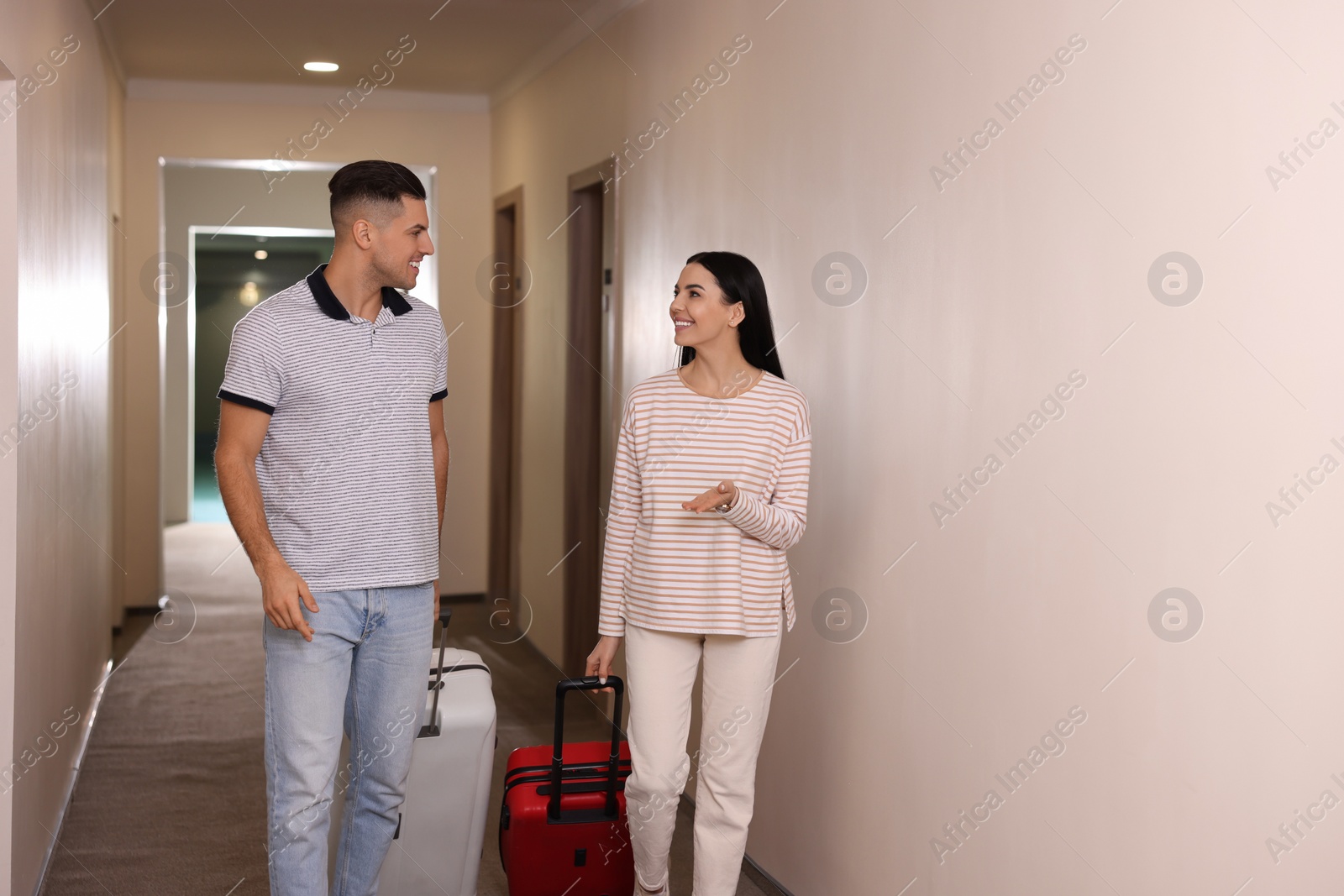 Photo of Happy couple with suitcases in hotel corridor