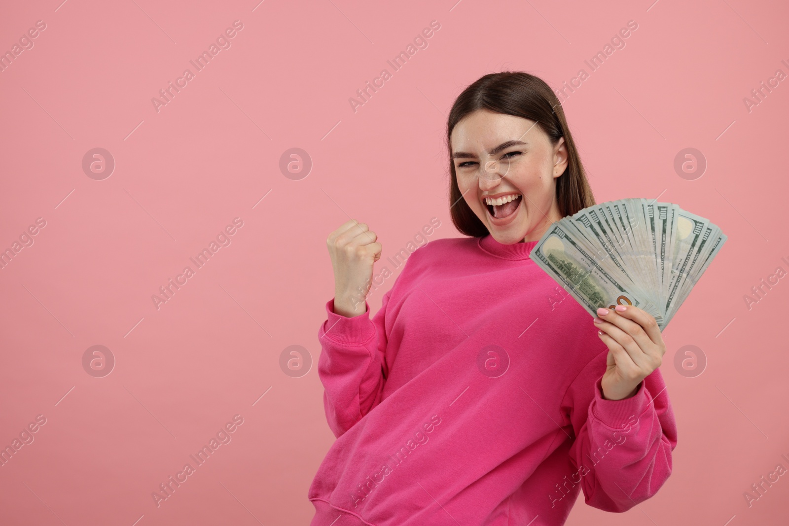 Photo of Happy woman with dollar banknotes on pink background, space for text