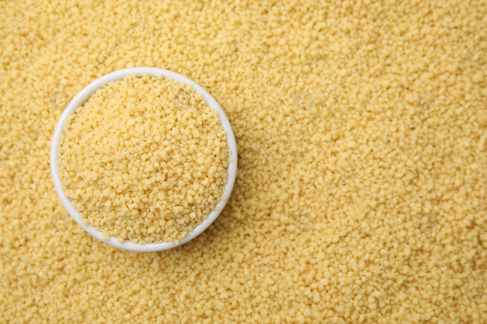 Photo of Bowl with raw couscous as background, top view. Space for text