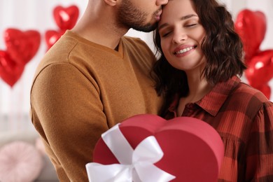 Photo of Happy couple celebrating Valentine's day. Beloved woman with gift box indoors