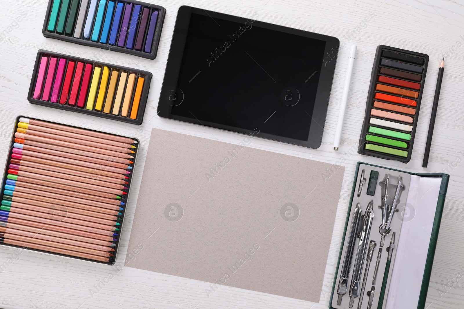 Photo of Layout with blank paper, soft pastels and other drawing supplies on white wooden table at artist's workplace, top view. Space for design