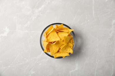 Photo of Tasty mexican nachos chips in glass bowl on grey table, top view