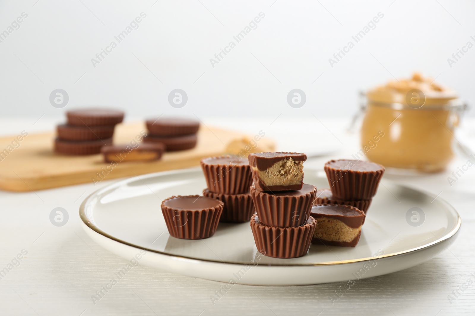 Photo of Cut and whole delicious peanut butter cups on white table