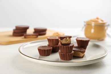 Photo of Cut and whole delicious peanut butter cups on white table