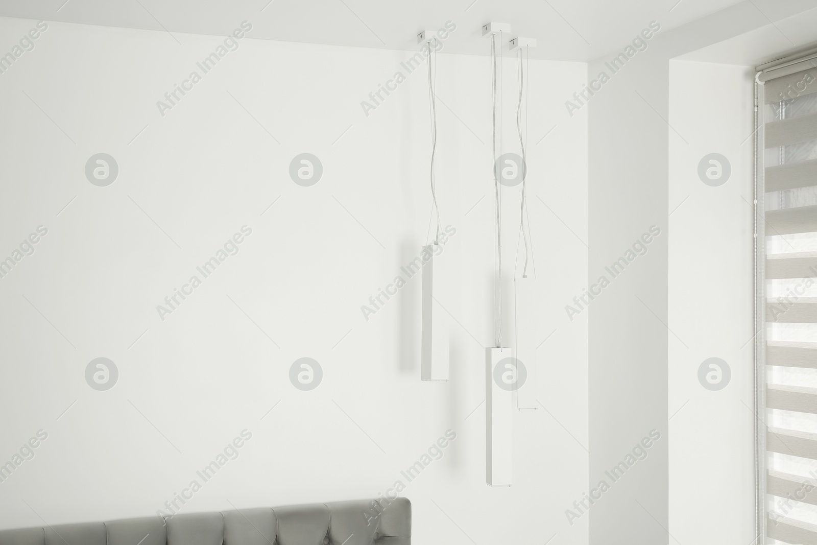 Photo of Stylish lamps hanging in light room. Space for text