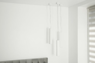 Photo of Stylish lamps hanging in light room. Space for text