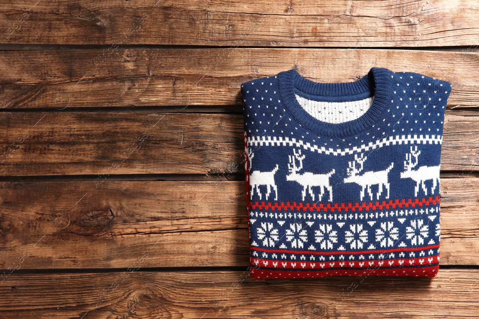 Photo of Christmas sweater with pattern and space for text on wooden background, top view