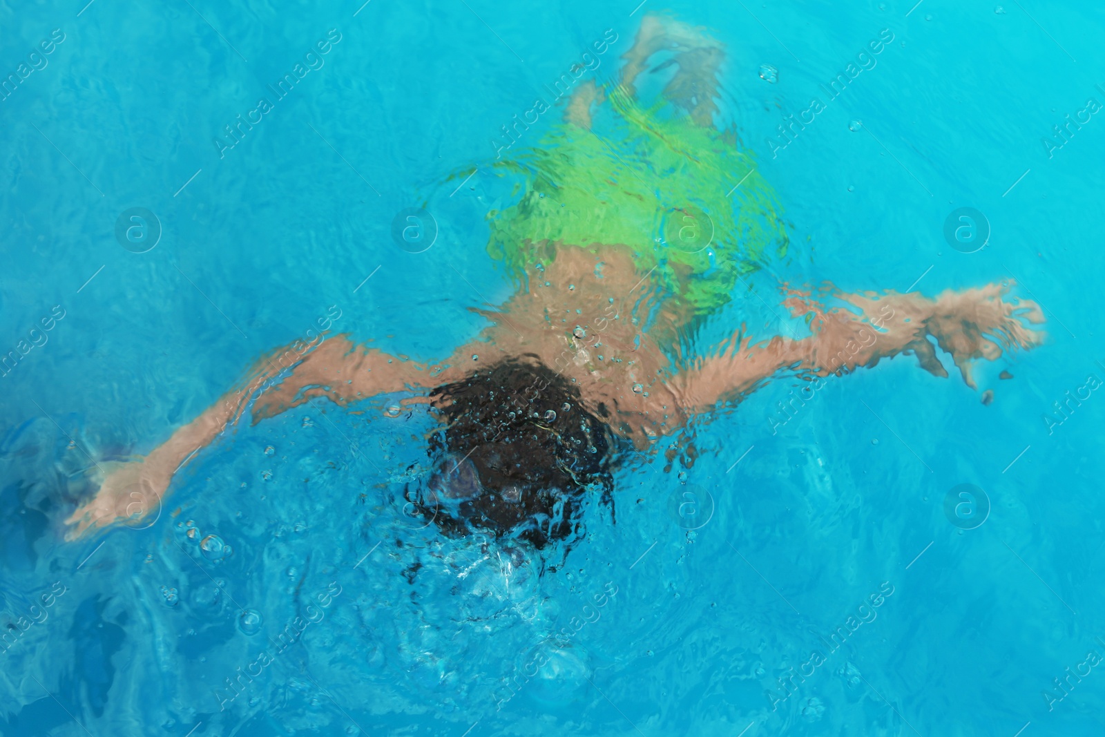 Photo of Little child under water in outdoor swimming pool. Dangerous situation