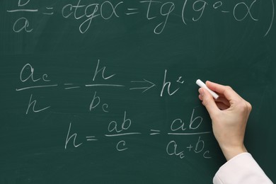 Photo of Teacher writing down math equation on green board, closeup