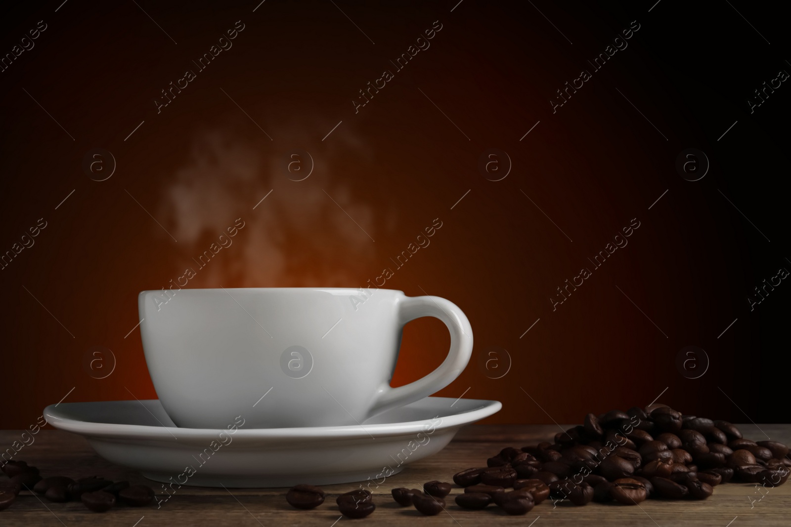 Image of Cup of hot aromatic coffee and roasted beans on wooden table against brown background