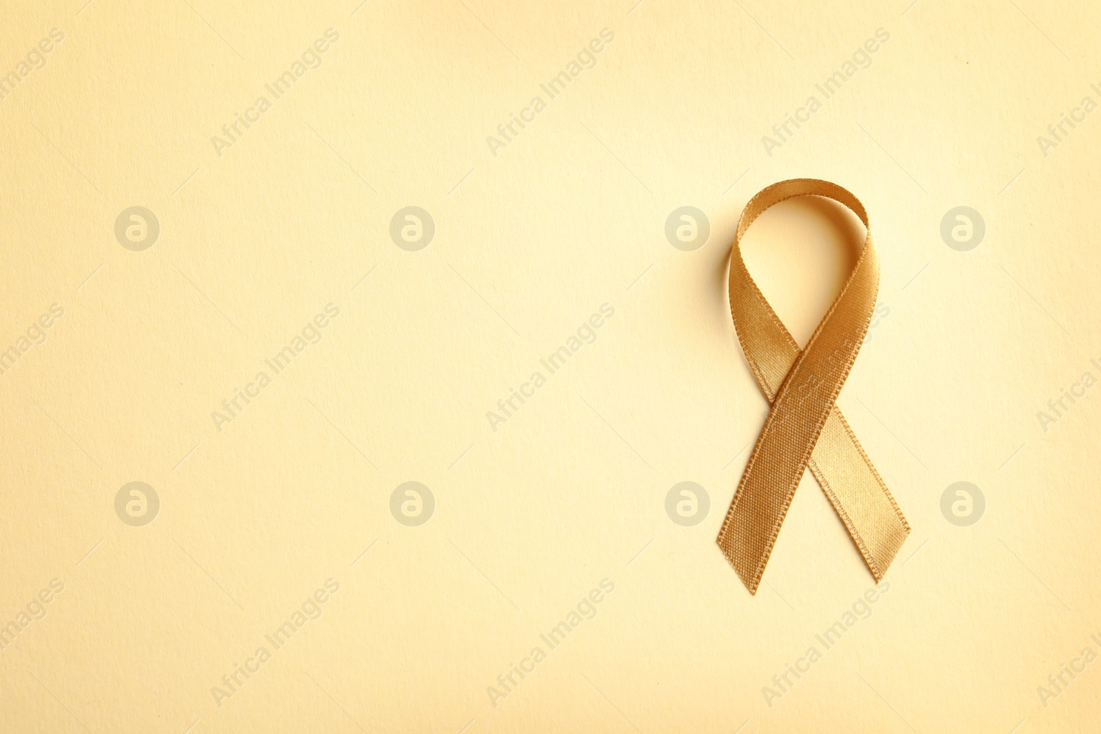 Photo of Gold ribbon on color background, top view. Cancer awareness