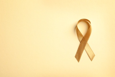Gold ribbon on color background, top view. Cancer awareness