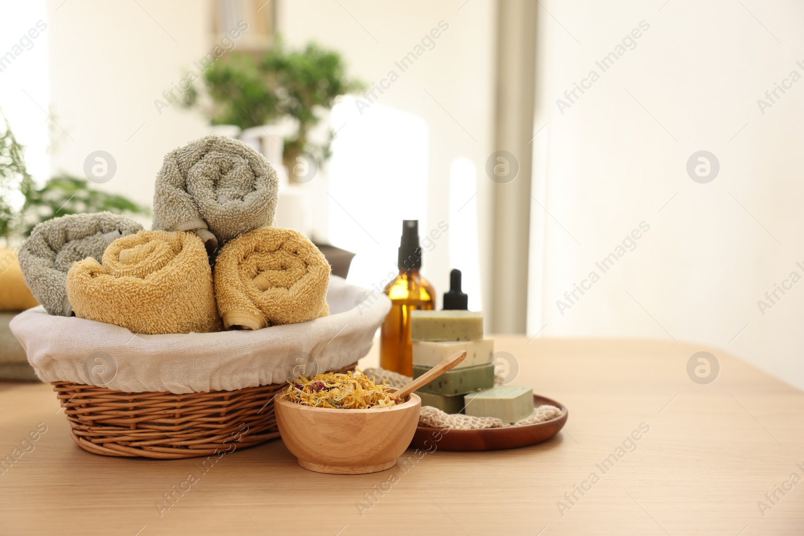 Photo of Dry flowers, soap bars, bottles of essential oils and towels on wooden table indoors, space for text. Spa time