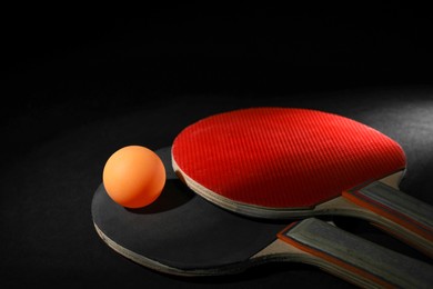 Ping pong ball and rackets on black background, closeup. Space for text