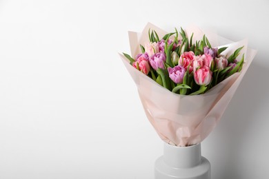 Vase with bouquet of beautiful tulips on white background. Space for text