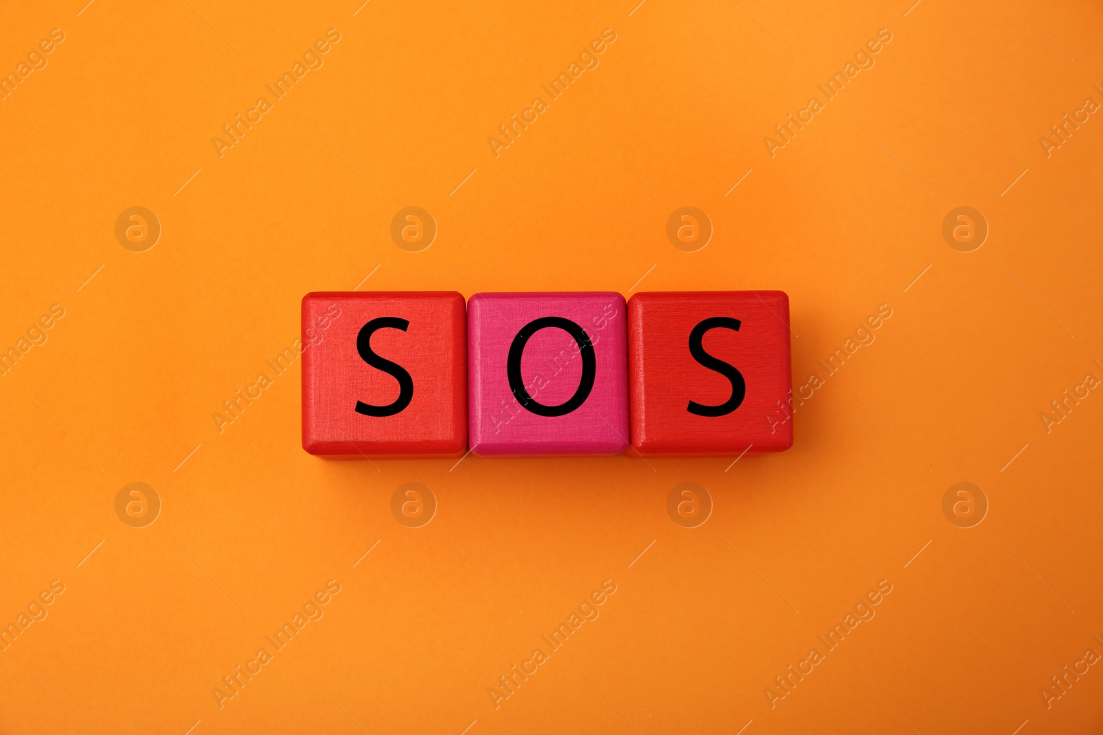 Photo of Abbreviation SOS (Save Our Souls) made of color cubes with letters on orange background, top view