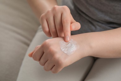 Photo of Woman applying ointment onto her hand, closeup