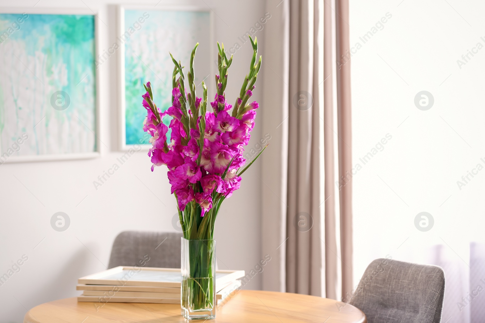 Photo of Vase with beautiful pink gladiolus flowers on wooden table in room, space for text