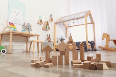 Wooden toy construction set on floor in playroom. Interior design