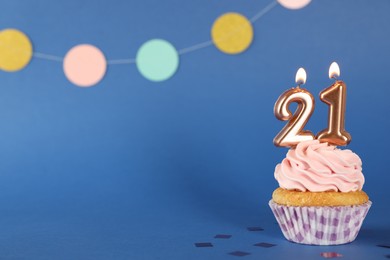 Photo of Delicious cupcake with number shaped candles on blue background, space for text. Coming of age party - 21th birthday