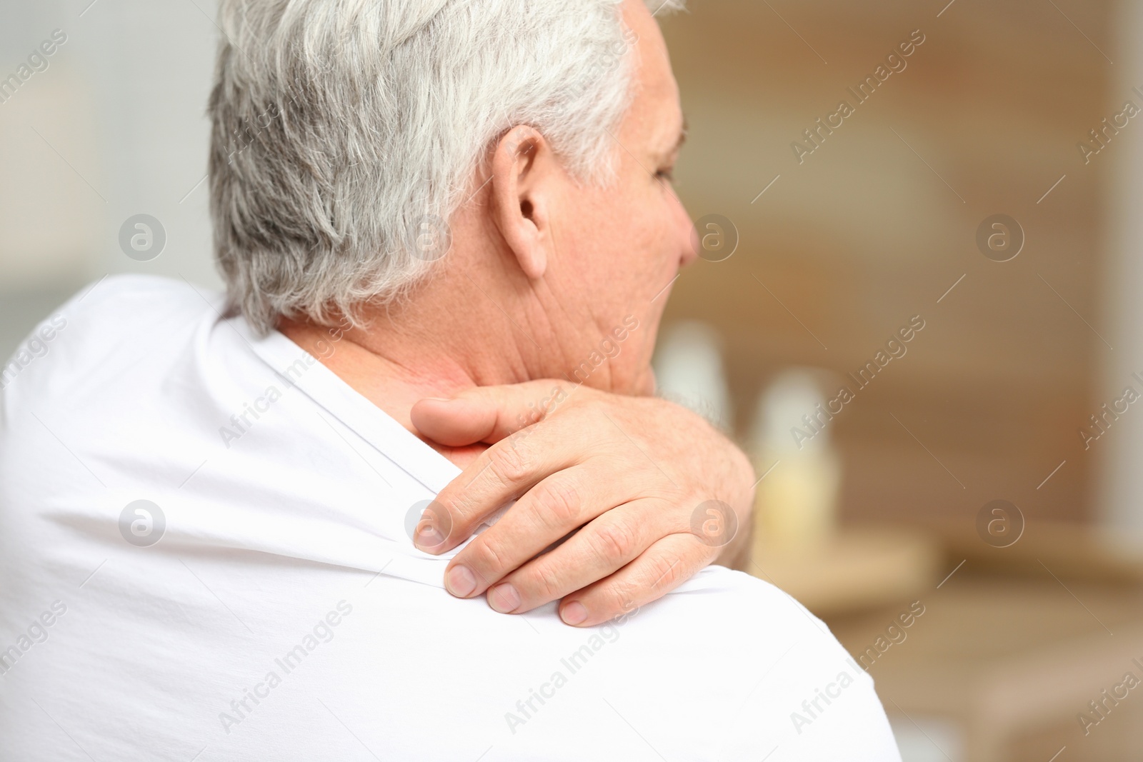 Photo of Senior man scratching shoulder indoors, closeup with space for text. Allergy symptom