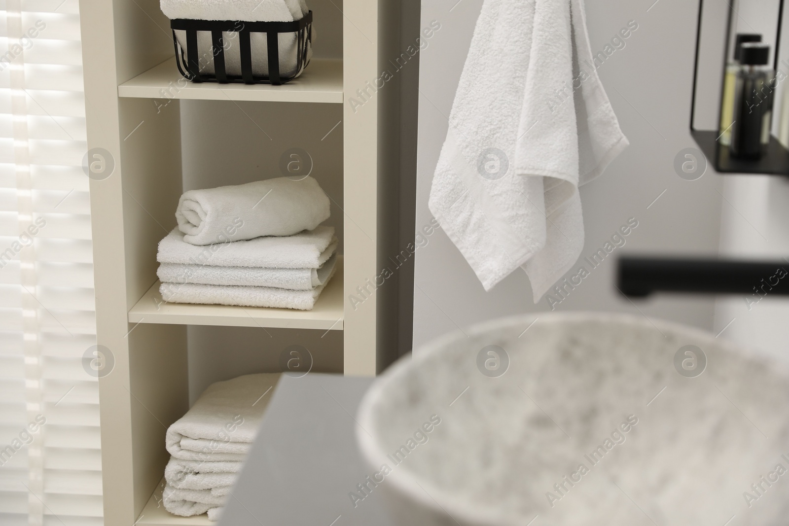 Photo of Shelving unit with stacked clean towels in bathroom