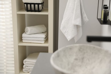 Shelving unit with stacked clean towels in bathroom