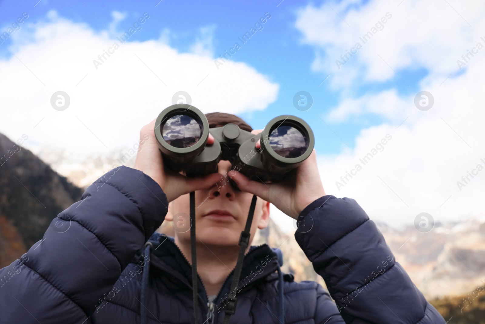 Photo of Boy looking through binoculars in beautiful mountains, closeup