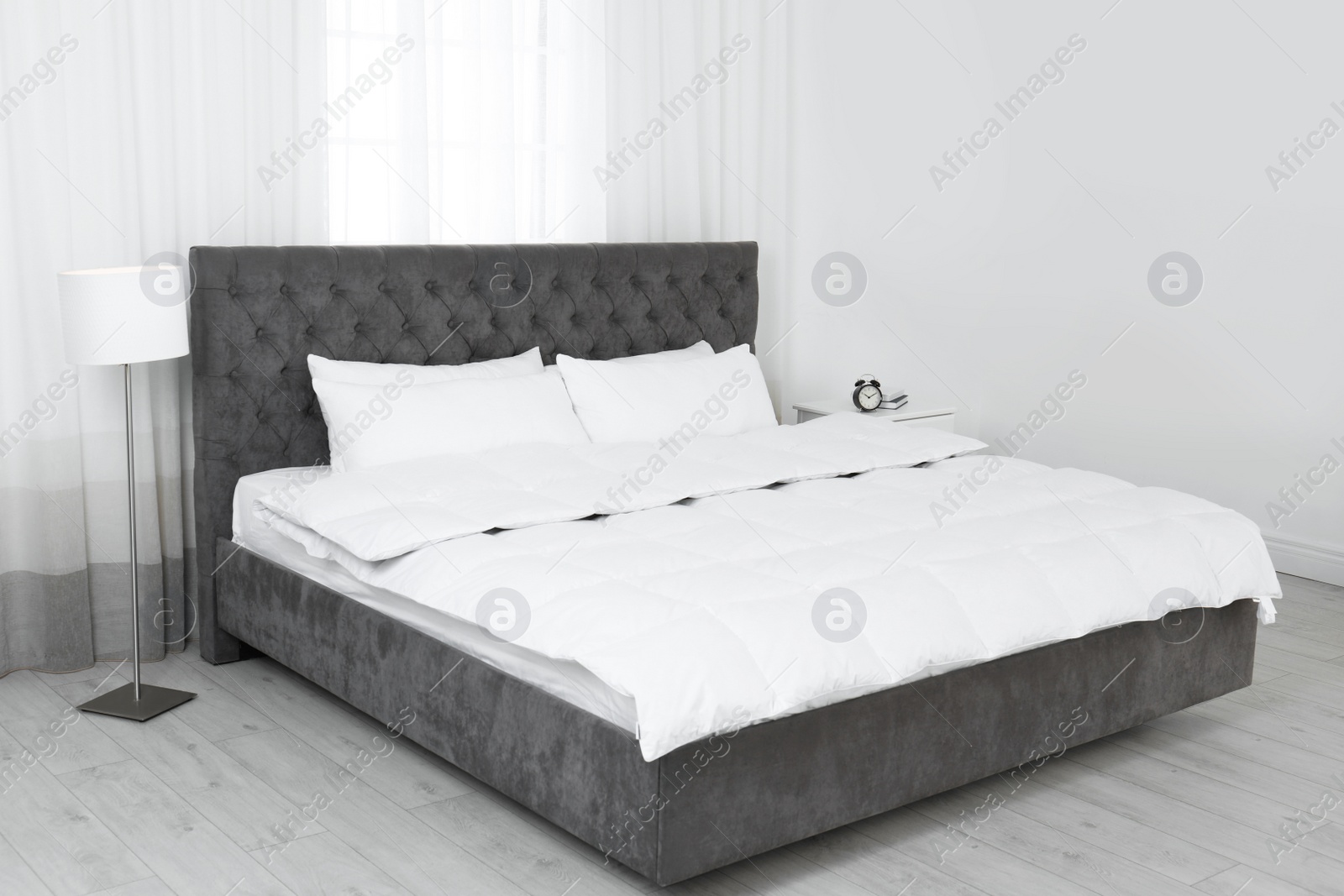 Photo of Large comfortable bed in light room. Stylish interior