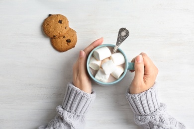 Photo of Woman with delicious hot cocoa drink at table, top view