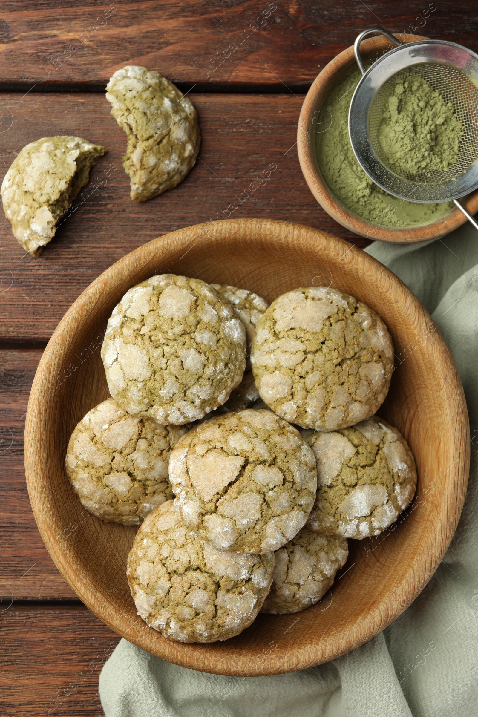 Photo of Bowl with tasty matcha cookies and powder on wooden table, flat lay
