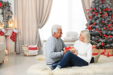 Happy mature couple with Christmas gift at home