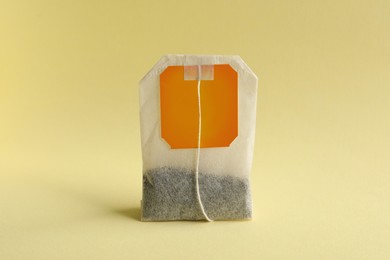 Photo of New tea bag with tab on yellow background, closeup
