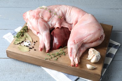 Photo of Whole raw rabbit, liver and spices on grey wooden table