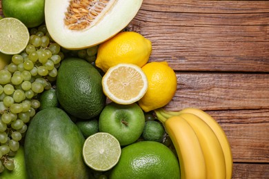 Photo of Many different fresh fruits and grapes on wooden table, flat lay. Space for text