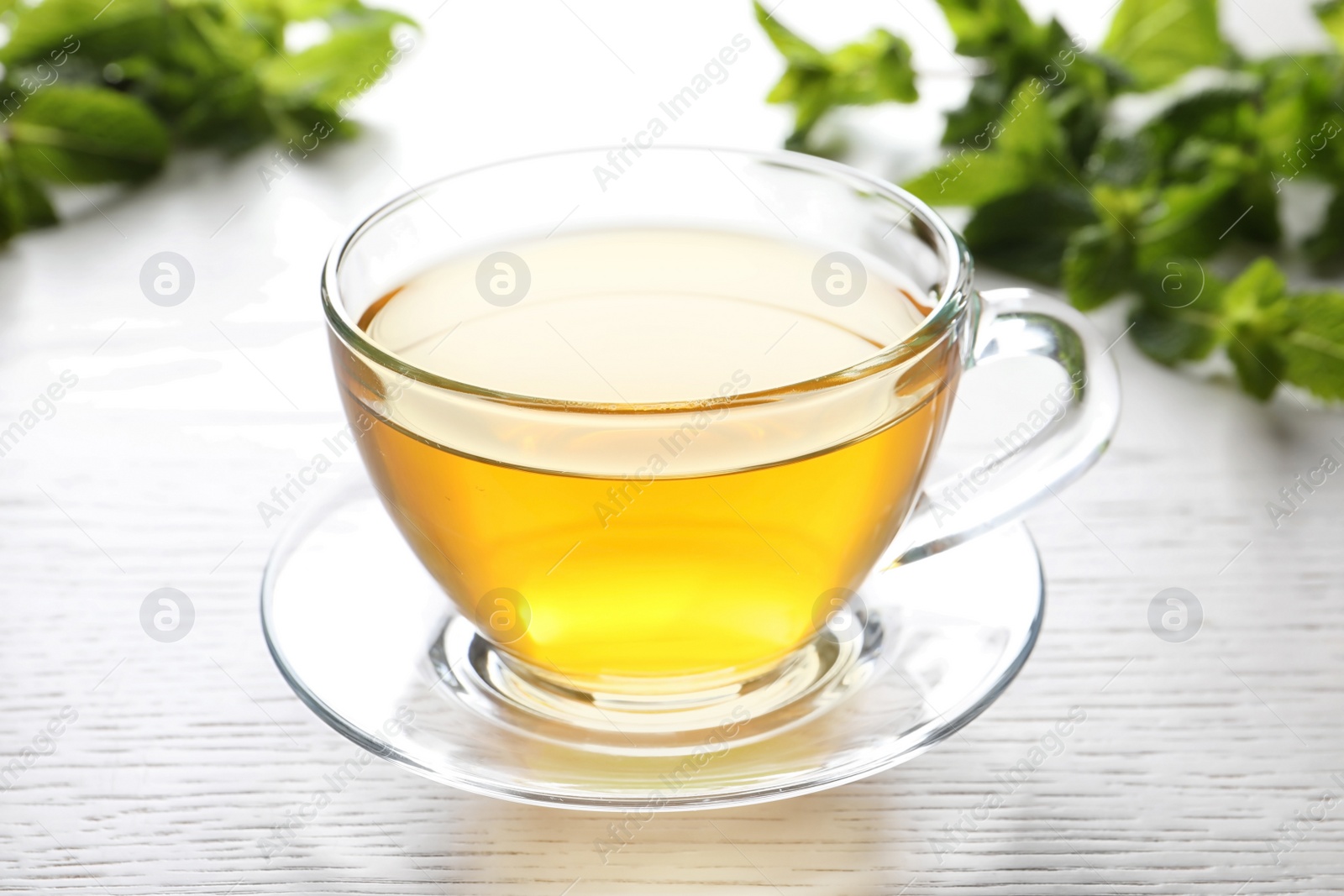 Photo of Cup with hot aromatic mint tea on table