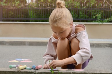 Photo of Little child drawing balloons with chalk on asphalt, space for text