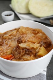 Photo of Tasty cabbage soup with meat and carrot on grey table, closeup