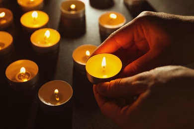 Photo of Young person holding burning candle in darkness, closeup