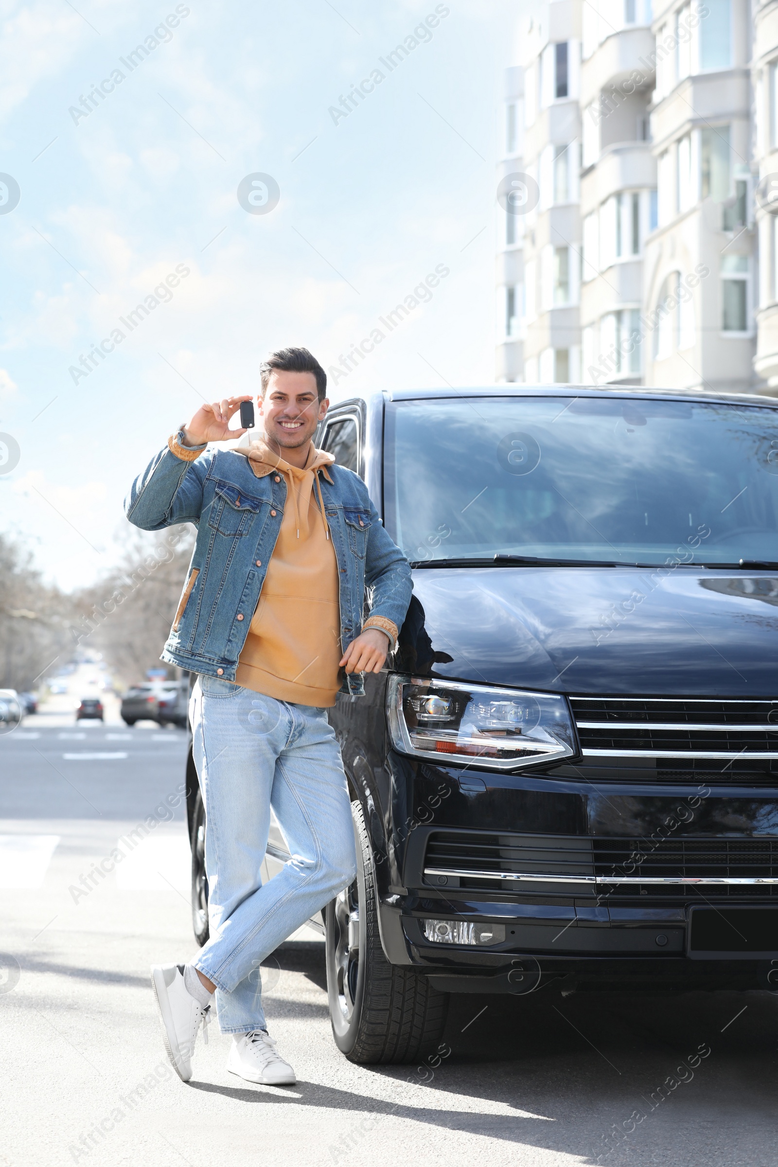 Photo of Man with key near car on city street. Buying new auto