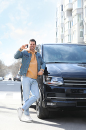 Photo of Man with key near car on city street. Buying new auto