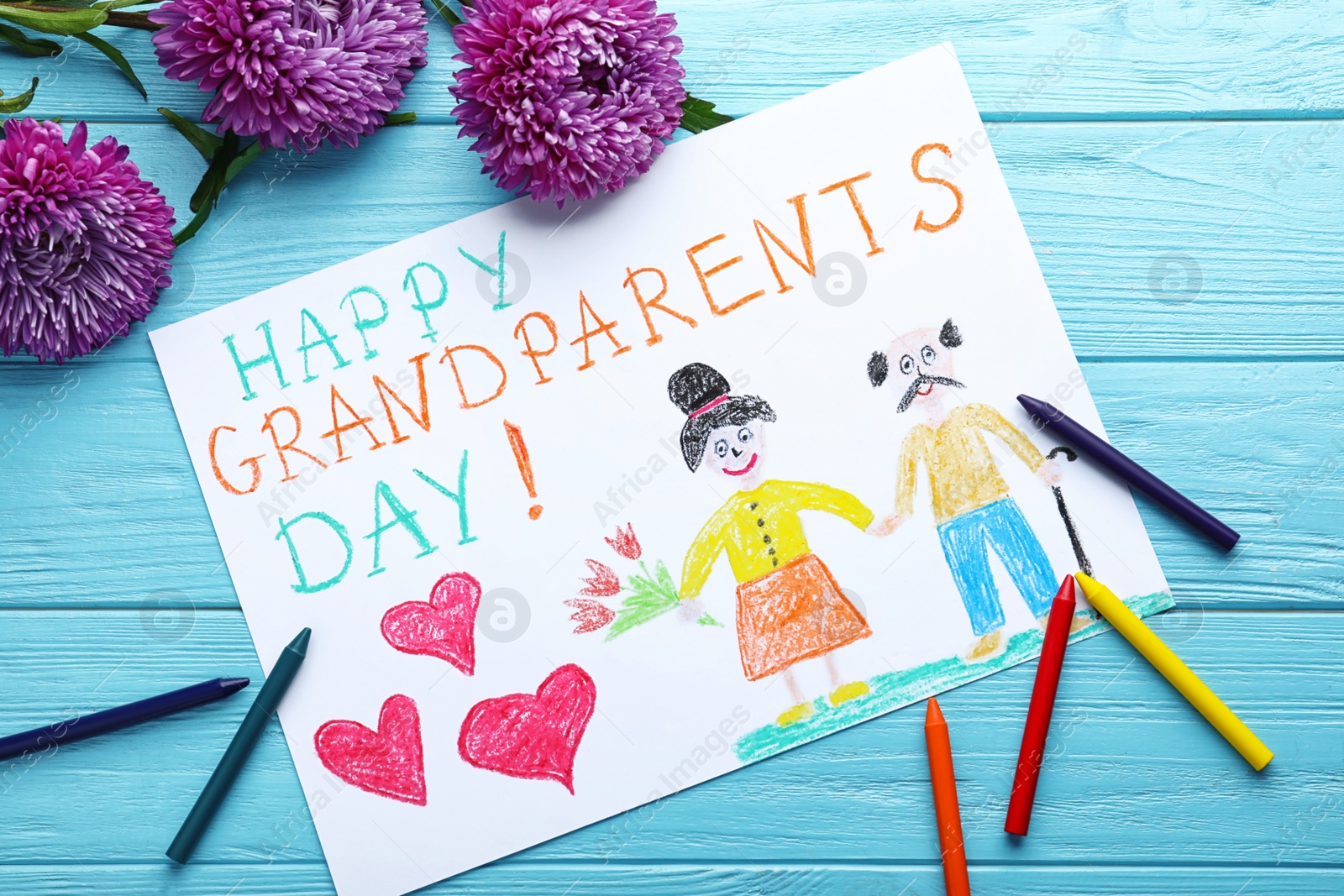 Photo of Beautiful drawing with phrase Happy Grandparents Day on blue wooden table, flat lay