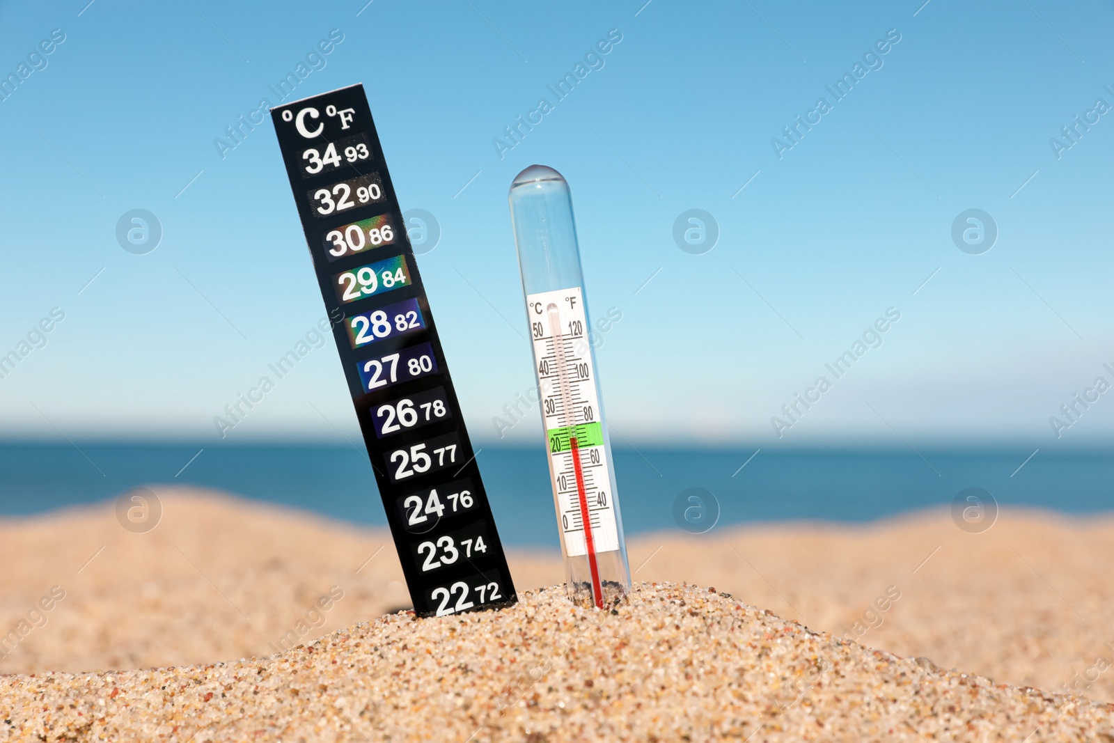 Photo of Weather thermometers in sand near sea, closeup