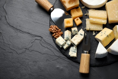 Photo of Flat lay composition with different sorts of cheese and knives on black table. Space for text