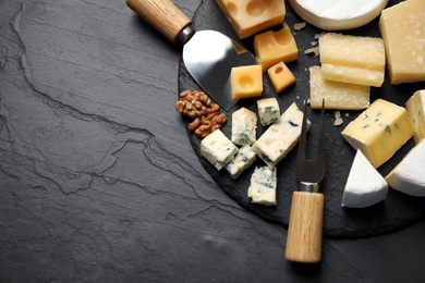 Flat lay composition with different sorts of cheese and knives on black table. Space for text