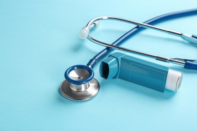Photo of Asthma inhaler and stethoscope on color background