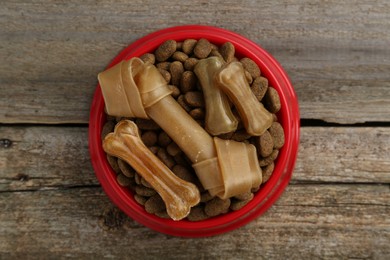 Dry dog food and treats (chew bones) on wooden floor, top view