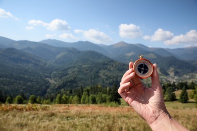 Photo of Woman with compass in mountains, closeup. Space for text