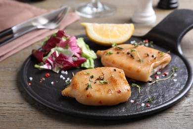 Photo of Grilled squid tubes served on wooden table, closeup